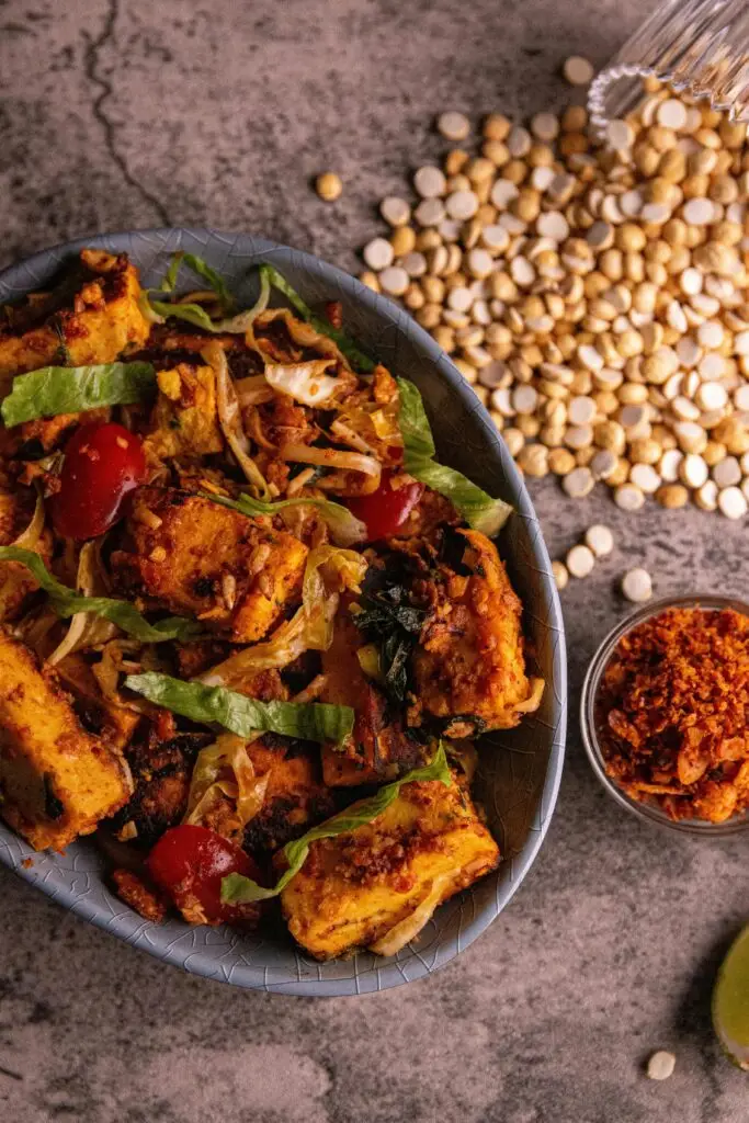 A delicious tofu stir-fry with cherry tomatoes, lettuce, and spices served in a rustic style.