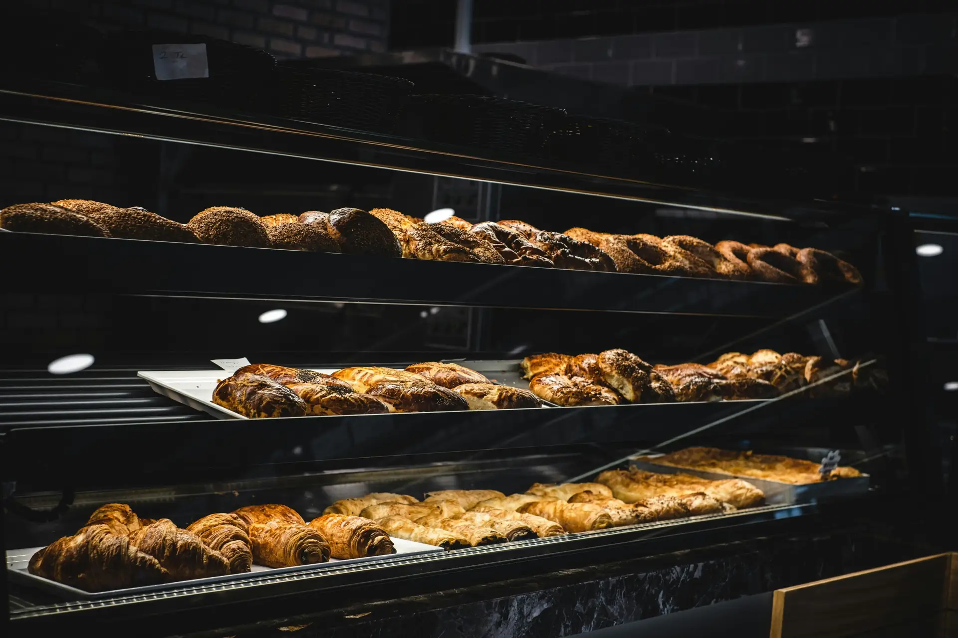A variety of freshly baked pastries and breads in a glass display case at a bakery.